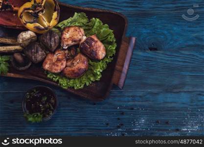 Grilled pork meat. Grilled pork meat with vegetable on a blue wooden background