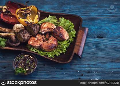 Grilled pork meat. Grilled pork meat with vegetable on a blue wooden background