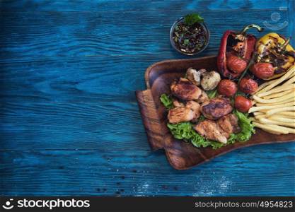 Grilled pork meat with vegetable on a blue wooden background. Grilled pork meat