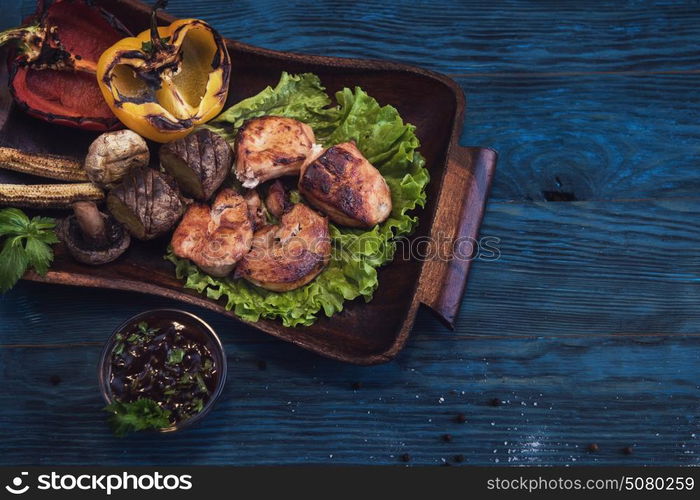 Grilled pork meat with vegetable on a blue wooden background. Grilled pork meat