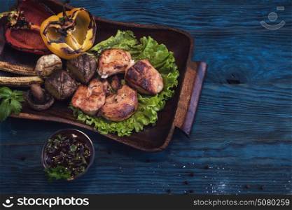 Grilled pork meat with vegetable on a blue wooden background. Grilled pork meat