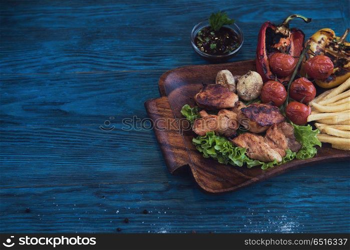 Grilled pork meat with vegetable on a blue wooden background. Grilled pork meat. Grilled pork meat