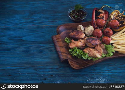 Grilled pork meat with vegetable on a blue wooden background. Grilled pork meat. Grilled pork meat