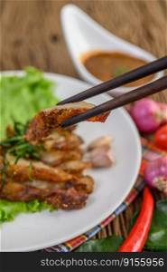 Grilled pork neck on a white plate on a wooden table. Selective focus