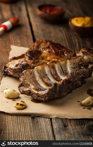 Grilled pork ribs with ketchup, mustard and garlic on a wooden table

