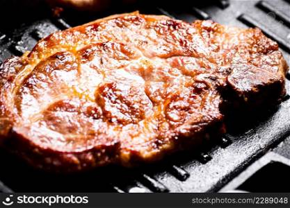 Grilled pork steak in a frying pan. Macro background. High quality photo. Grilled pork steak in a frying pan. Macro background.