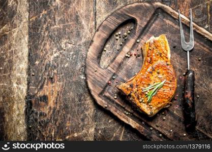 Grilled pork steak with spices. On wooden background.. Grilled pork steak with spices.