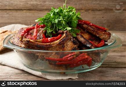 grilled pork steaks on the bone lie in a transparent glass plate on a wooden table, barbecue