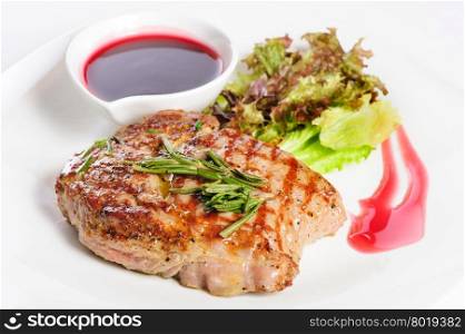 Grilled pork steaks with raspberry sauce, rosemary and leaf of lettuce