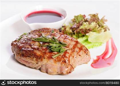 Grilled pork steaks with raspberry sauce, rosemary and leaf of lettuce