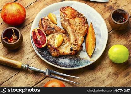 Grilled pork with red orange sauce on old wooden table. Meat fried in orange sauce.