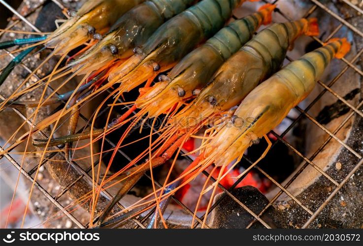Grilled prawn on charcoal grill. Giant freshwater prawns grill on a flaming charcoal fire. Closeup giant river prawn cooking on barbecue grill rack. Cooking food for the party. Thai food culture.