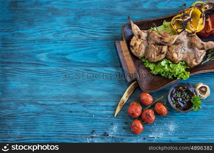 Grilled quail meat. Grilled quail meat with vegetable on a blue wooden background