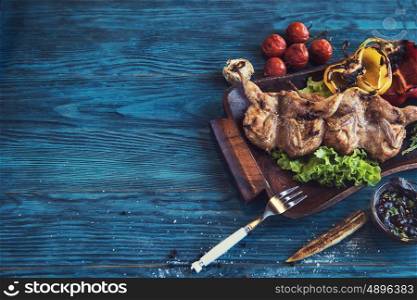 Grilled quail meat with vegetable on a blue wooden background. Grilled quail meat