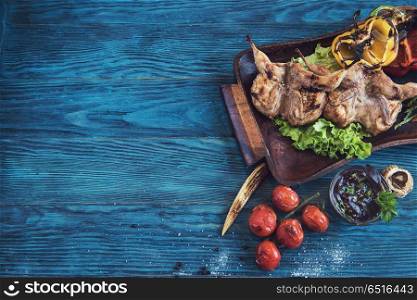 Grilled quail meat with vegetable on a blue wooden background. Grilled quail meat. Grilled quail meat