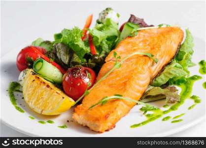Grilled salmon and fresh vegetable salad at the plate. Grilled salmon and vegetables