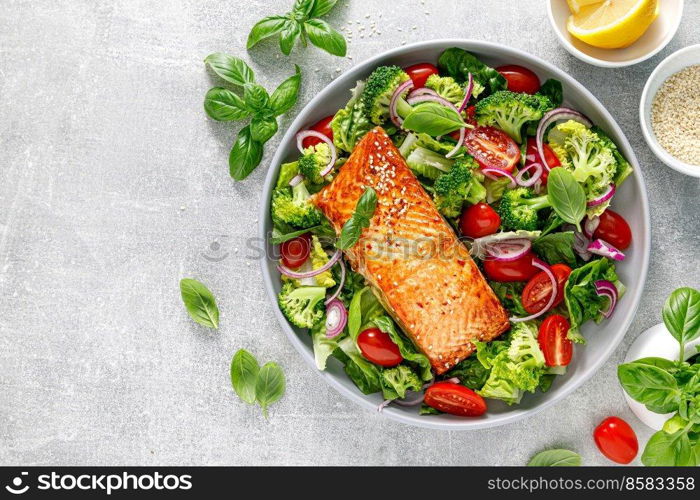 Grilled salmon fish fillet and fresh green leafy vegetable salad with tomatoes, red onion and broccoli. Healthy food. Ketogenic lunch. Top view