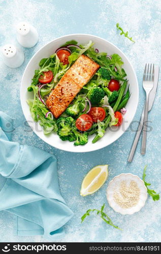 Grilled salmon fish fillet and fresh tomato vegetable salad with lettuce, arugula, broccoli and green beans. Healthy food, mediterranean diet