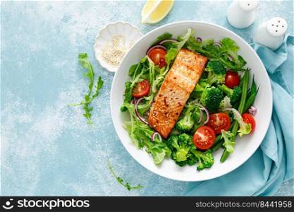 Grilled salmon fish fillet and fresh tomato vegetable salad with lettuce, arugula, broccoli and green beans. Healthy food, mediterranean diet