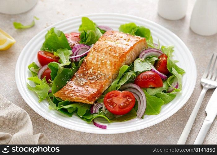 Grilled salmon fish fillet and fresh vegetable salad with tomato, red onion and lettuce