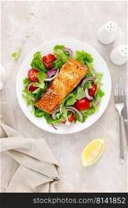 Grilled salmon fish fillet and fresh vegetable salad with tomato, red onion and lettuce