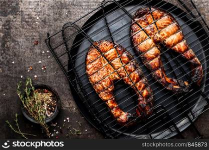 Grilled salmon on iron grill grate on a dark background top view. BBQ seafood. spece for a text