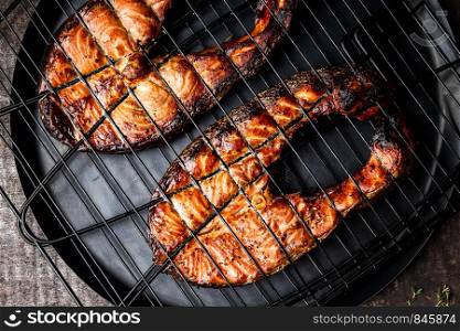 Grilled salmon on iron grill grate on a dark background top view. BBQ seafood