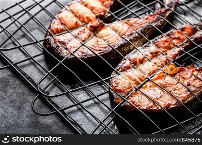Grilled salmon on iron grill grate on a dark background top view. BBQ seafood. spece for a text