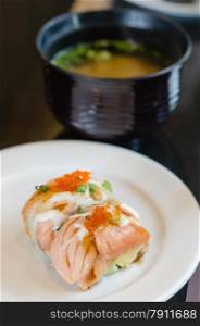 grilled salmon roll sushi with shrimp egg on top in white dish served with miso soup. Salmon roll sushi