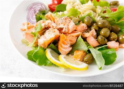 Grilled salmon salad with fresh lettuce, tomatoes, green olives, red onion and pasta. Healthy food, diet