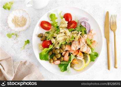 Grilled salmon salad with fresh lettuce, tomatoes, green olives, red onion and pasta. Healthy food, diet. Top view