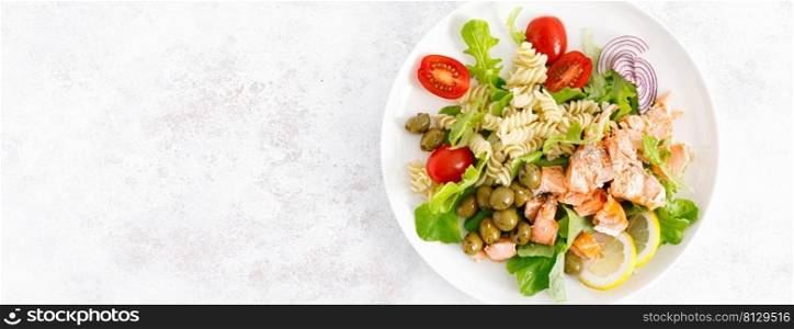 Grilled salmon salad with fresh lettuce, tomatoes, green olives, red onion and pasta. Healthy food, diet. Top view. Banner
