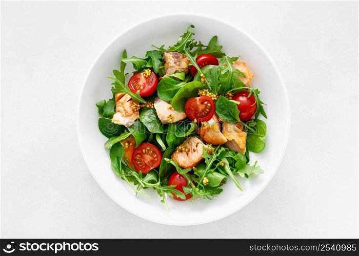 Grilled salmon salad with tomato and salad mix. Top view