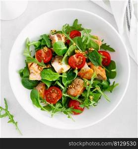 Grilled salmon salad with tomato and salad mix. Top view