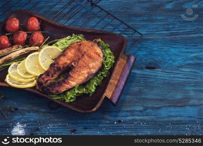 Grilled salmon steak. Grilled salmon steak with vegetable on a blue wooden background