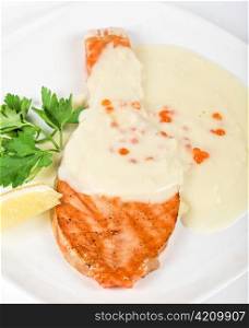 Grilled salmon steak with cheese sauce, greens, lemon and red caviar