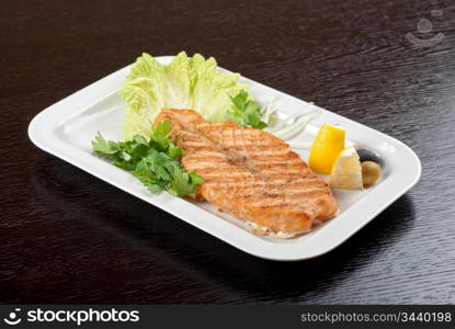 Grilled salmon steak with greens,onion, lemon, lime and olive