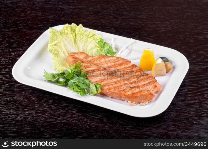 Grilled salmon steak with greens,onion, lemon, lime and olive