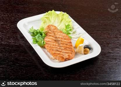 Grilled salmon steak with greens,onion, lemon, lime and olive
