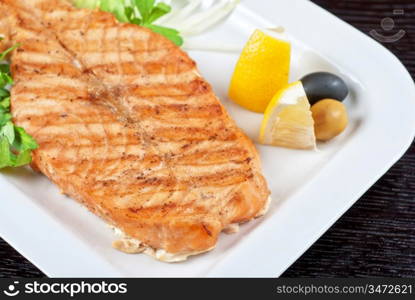 Grilled salmon steak with greens,onion, lemon, lime and olive