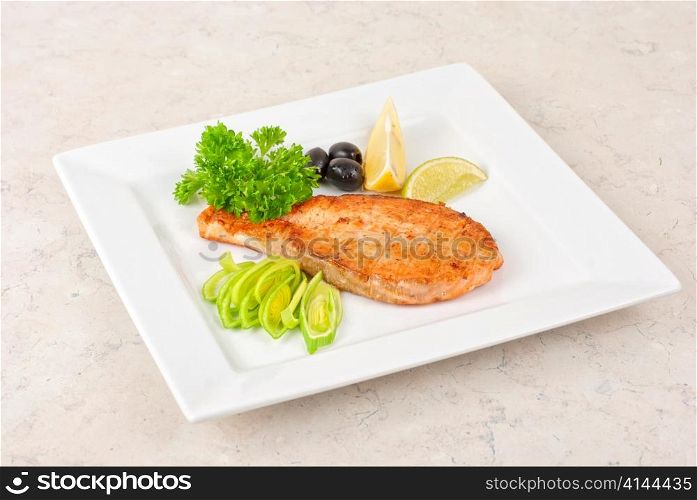Grilled salmon steak with greens,onion, lemon, lime and olive