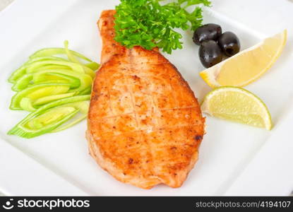 Grilled salmon steak with greens,onion, lemon, lime and olive