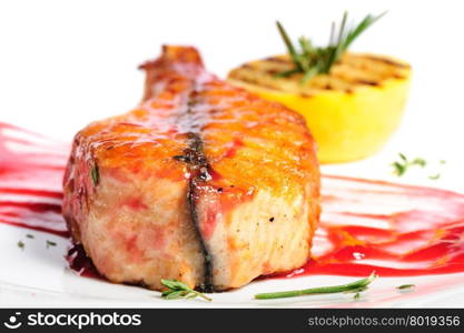 Grilled salmon steak with red sauce, lemon and rosemary, on white