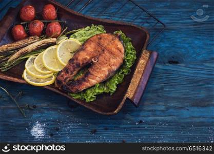 Grilled salmon steak with vegetable on a blue wooden background. Grilled salmon steak. Grilled salmon steak