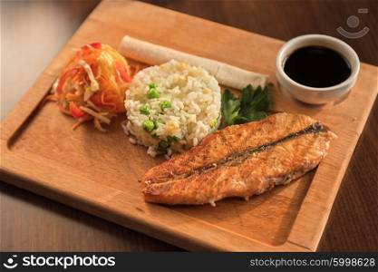 Grilled salmon with rice and vegetables at wooden table. Grilled salmon with rice