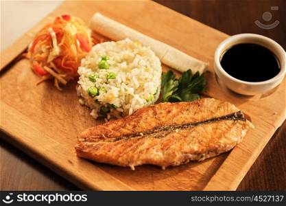 Grilled salmon with rice. Grilled salmon with rice and vegetables at wooden table