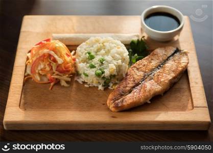 Grilled salmon with rice. Grilled salmon with rice and vegetables at wooden table