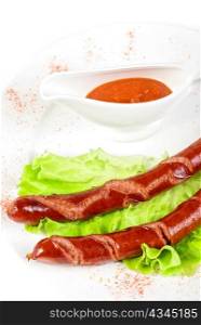 grilled sausage closeup with lettuce and sauce isolated on white