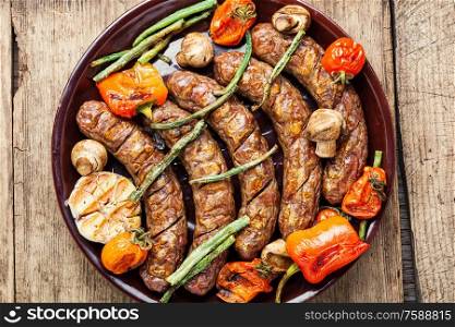 Grilled sausage with mushrooms and tomato.Fried sausages on wooden table. Sausages fried with vegetable
