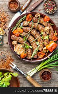 Grilled sausage with mushrooms and tomato.Fried sausages on wooden table. Tasty grilled sausages